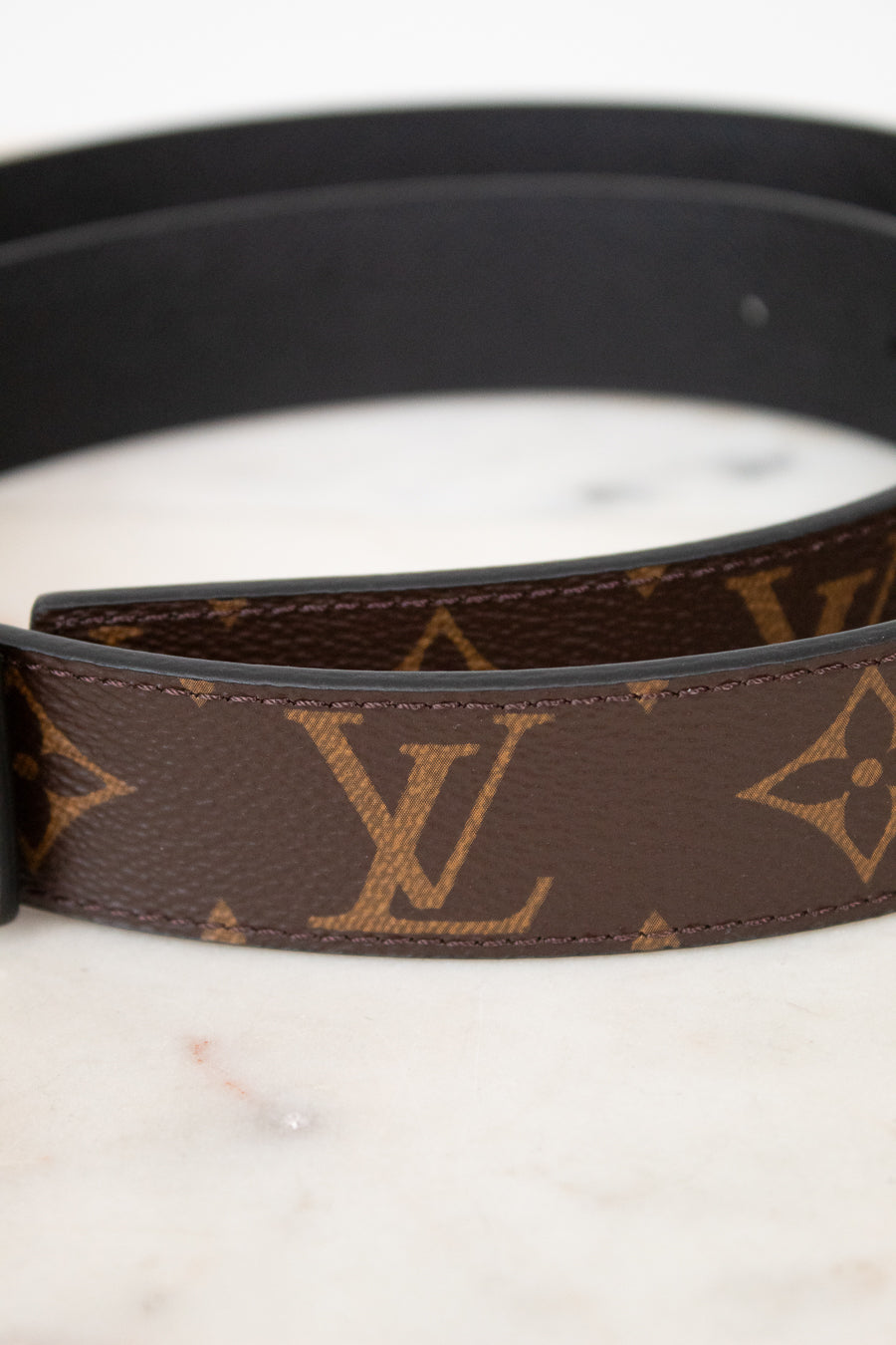 Louis Vuitton belt close up with monogram pattern on a marble surface