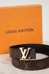 Louis Vuitton belt with monogram pattern and gold buckle with orange box background