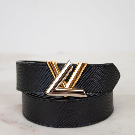 Black belt with a two tone buckle on a light marble background