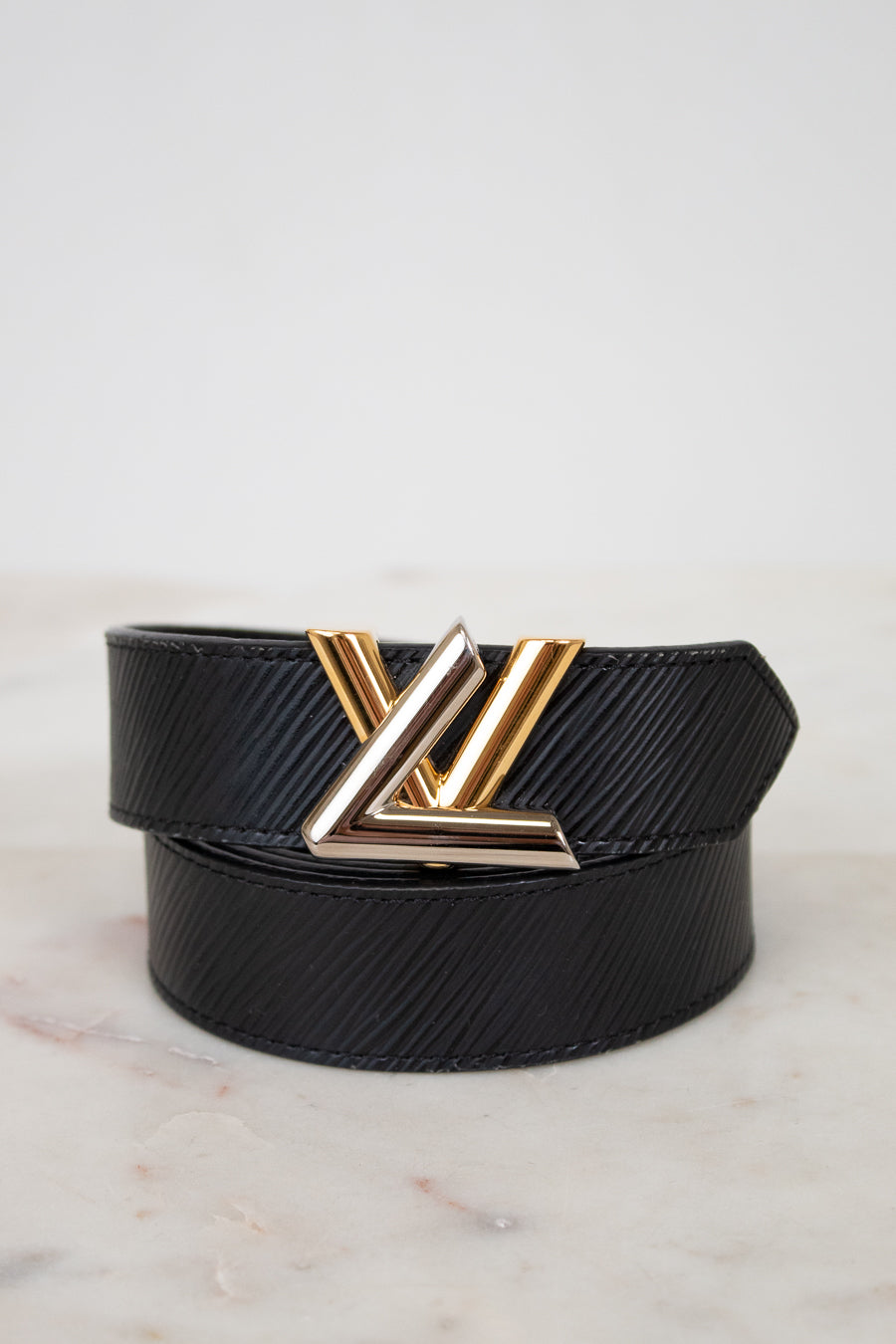 Black belt with a two tone buckle on a light marble background