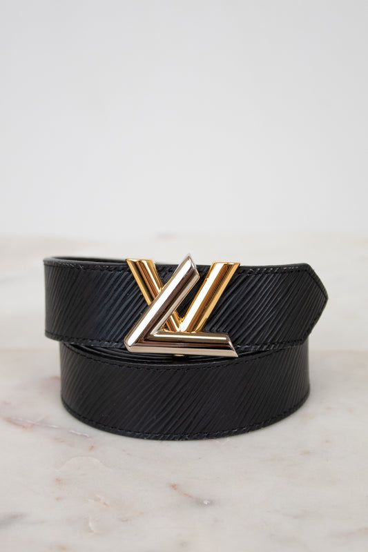 Black belt with a two tone buckle on a light marble background