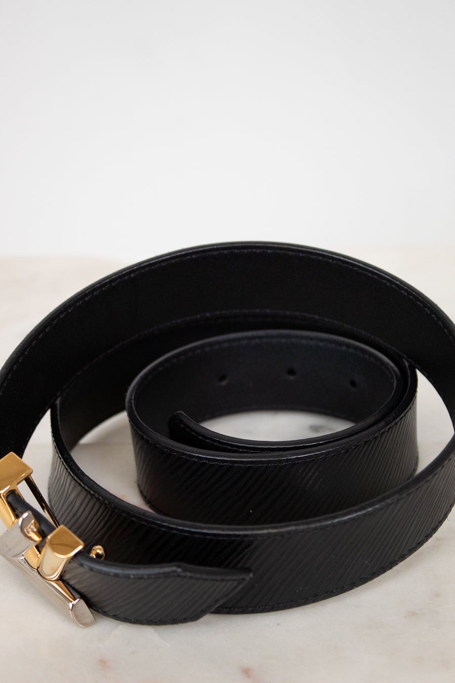 Black belt with two tone buckle on a marble surface