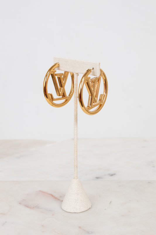 Gold hoop earrings on a white stand with a light background