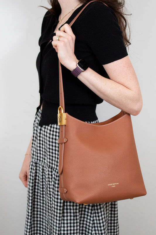 Person holding a brown leather bag with a plain background