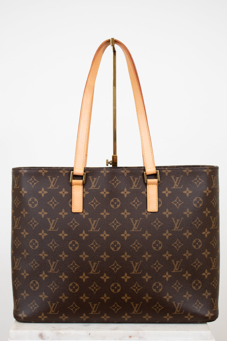 Brown monogram handbag with tan handles on a white background