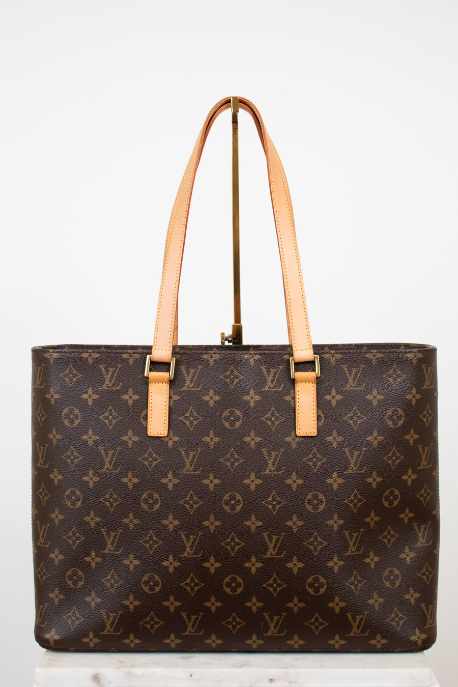 Brown monogram handbag with tan handles on a white background