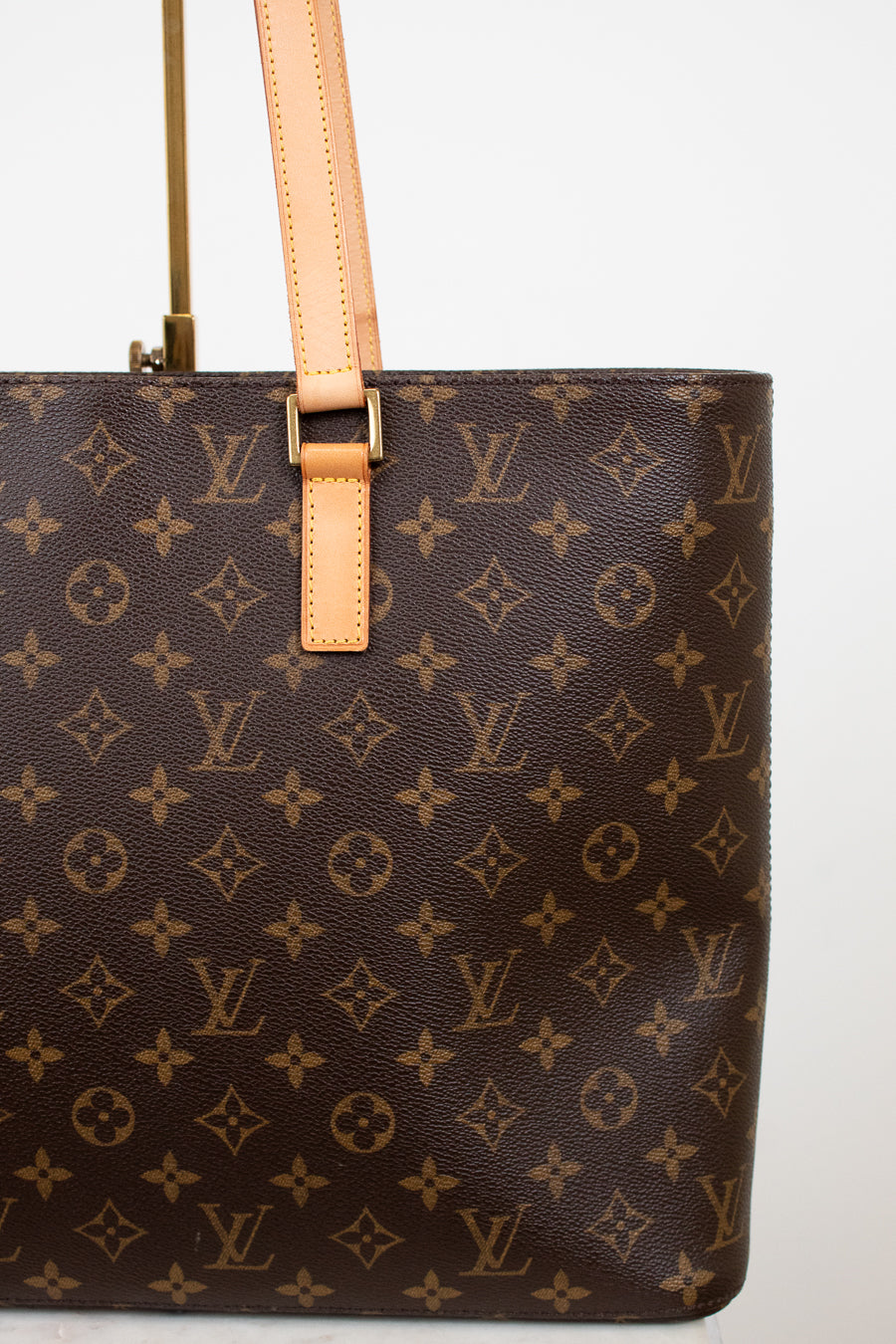 Brown monogram handbag with tan handles on a white background