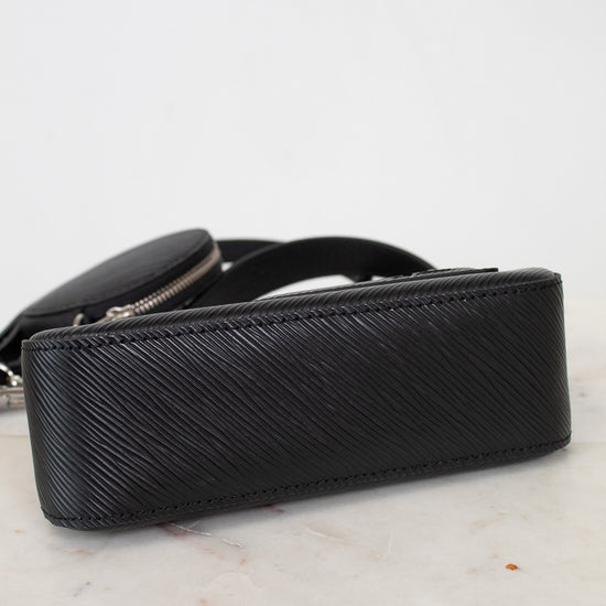 Bottom of black textured handbag on a marble surface with a light gray background