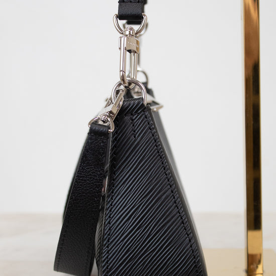 Black textured handbag with strap on a marble surface