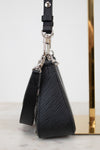 Black textured handbag with strap on a marble surface