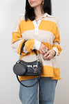 Person wearing a yellow and beige striped shirt with a black handbag on a plain background