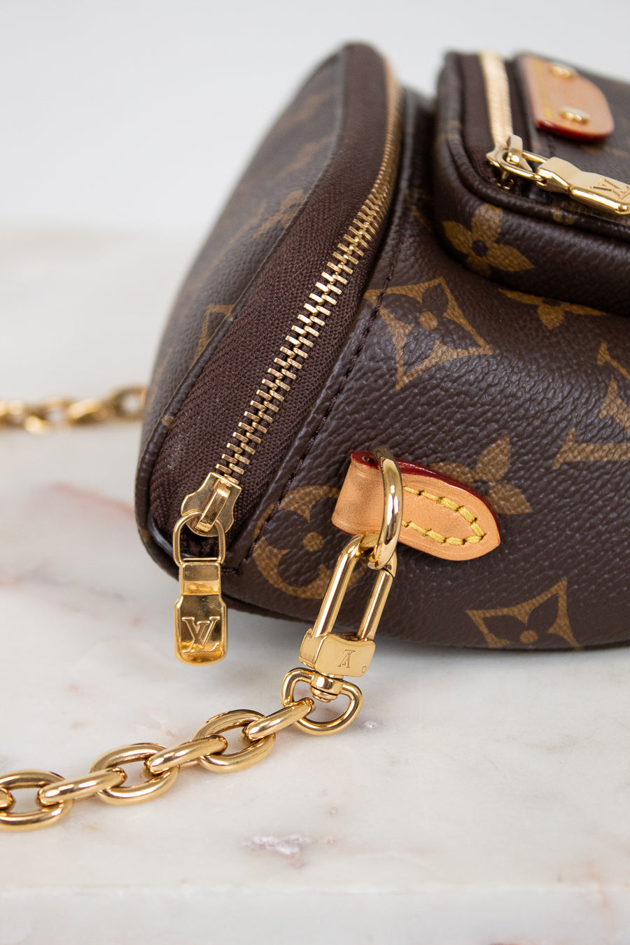 Brown handbag with gold chain strap on a marble surface