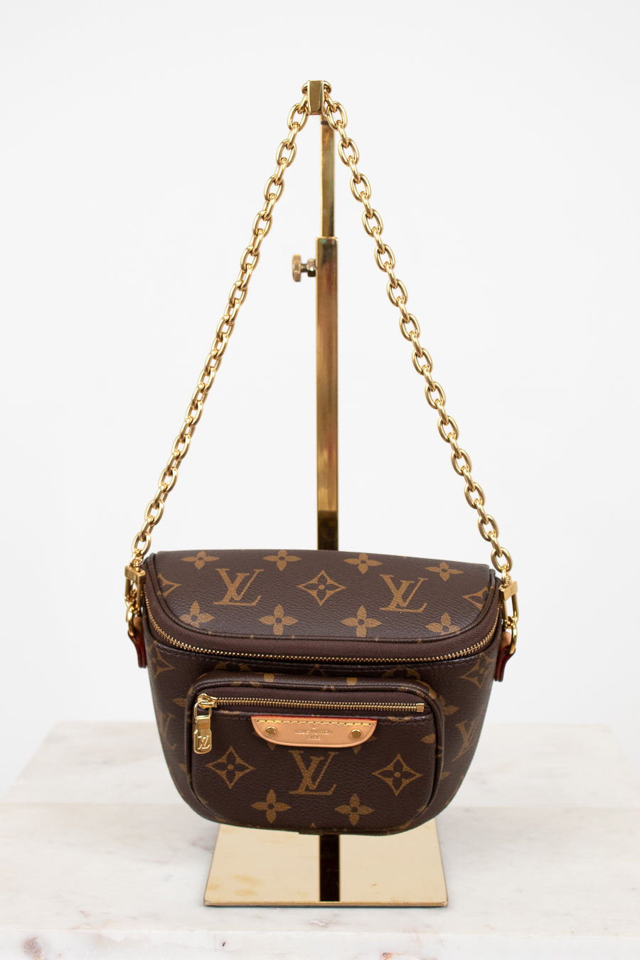 Louis Vuitton handbag with monogram pattern on a stand against a white background