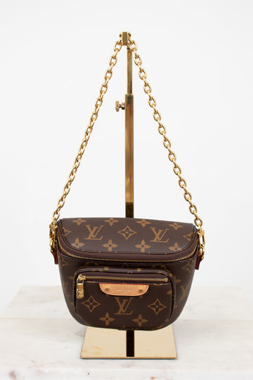 Louis Vuitton handbag with monogram pattern on a stand against a white background