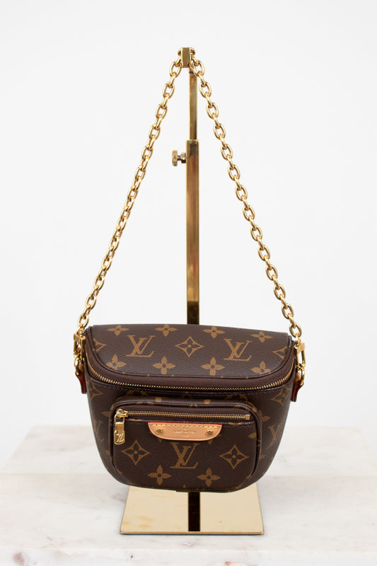 Louis Vuitton handbag with monogram pattern on a stand against a white background