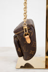 Brown leather pouch with gold chain and clasp on a reflective surface