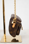 Louis Vuitton handbag with monogram pattern and gold chain on a stand.