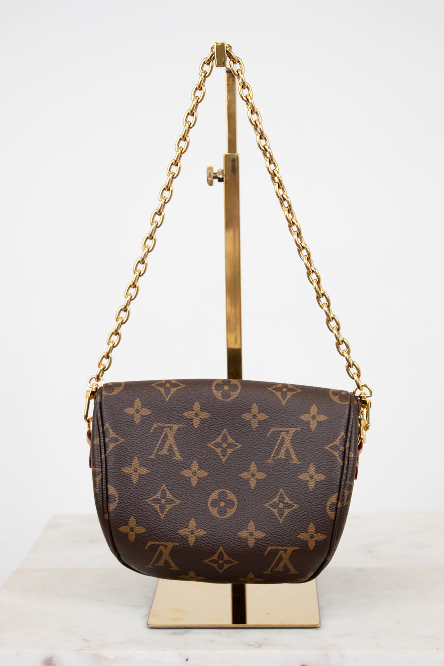 Designer handbag with gold chain and stand on a white background