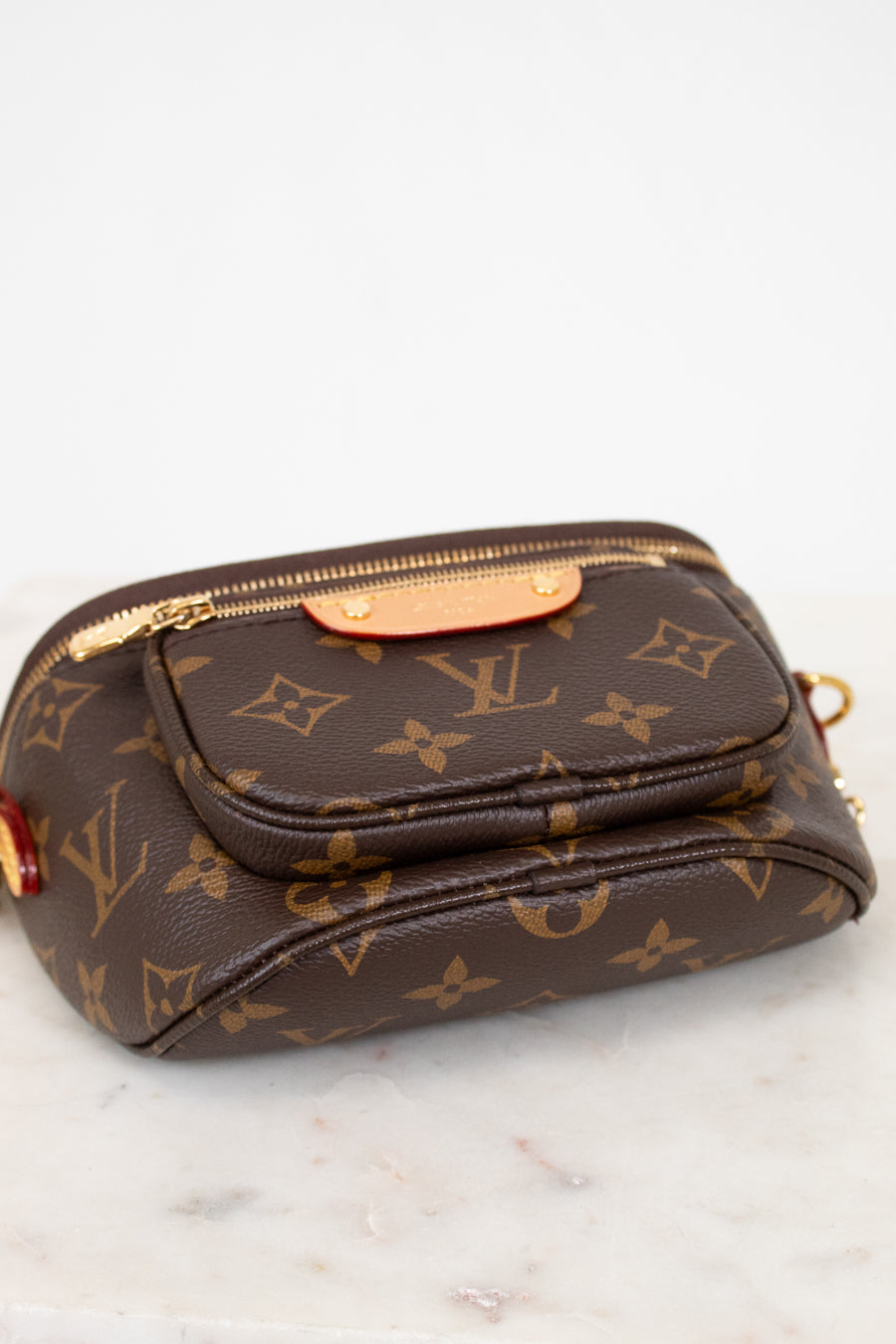 Brown Louis Vuitton handbag with monogram pattern on a white marble surface