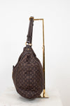 Brown monogram handbag on a gold stand against a white background