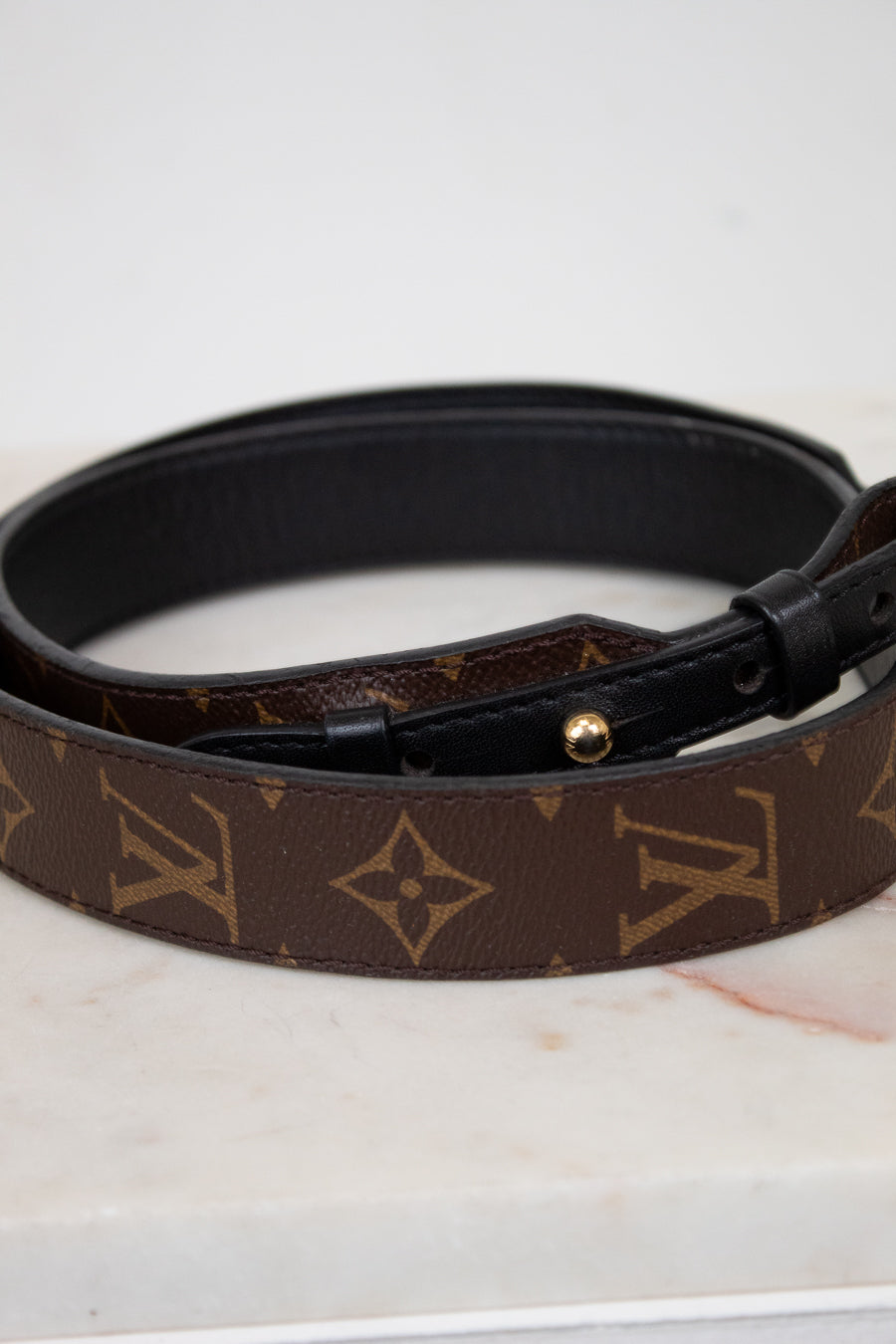 Louis Vuitton handbag strap with monogram pattern on a marble surface