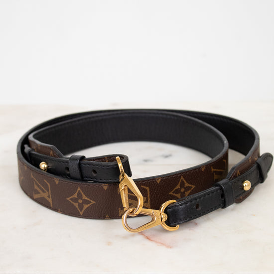 Designer belt with monogram pattern and gold buckle on a white background