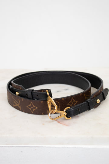 Designer belt with monogram pattern and gold buckle on a white background