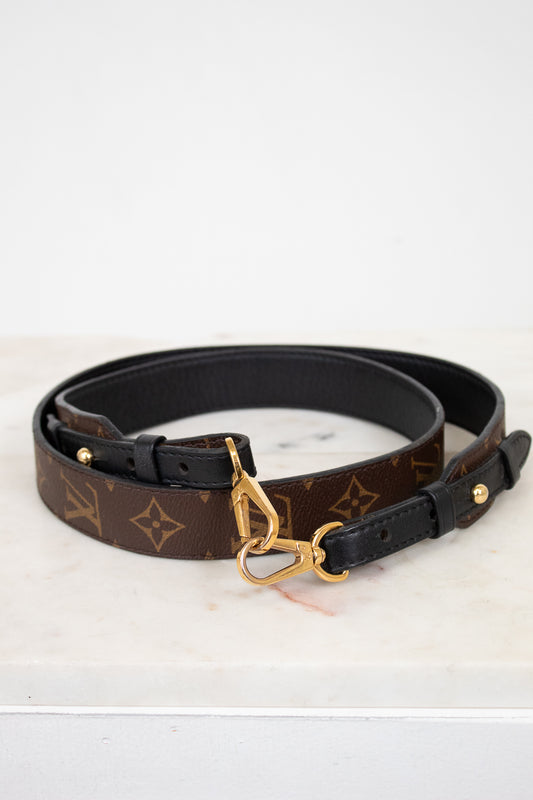 Designer belt with monogram pattern and gold buckle on a white background