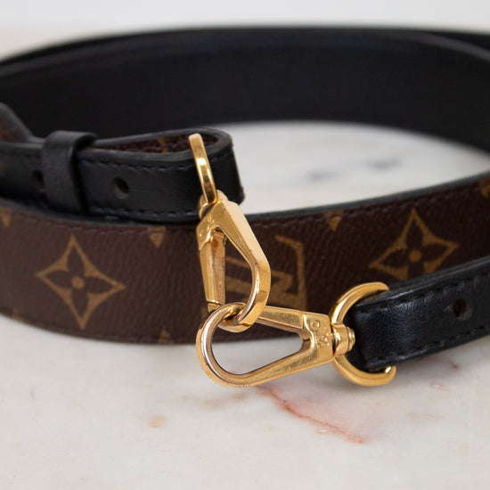 Handbag strap with gold clasp on a marble surface