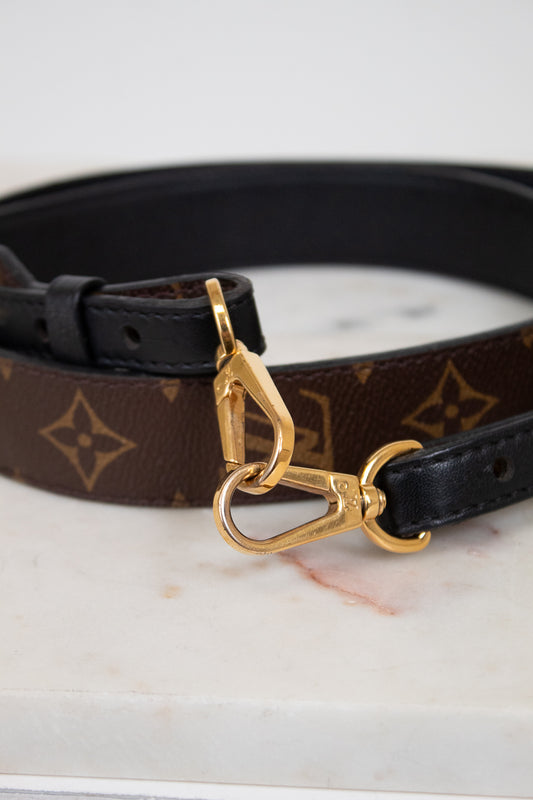 Handbag strap with gold clasp on a marble surface