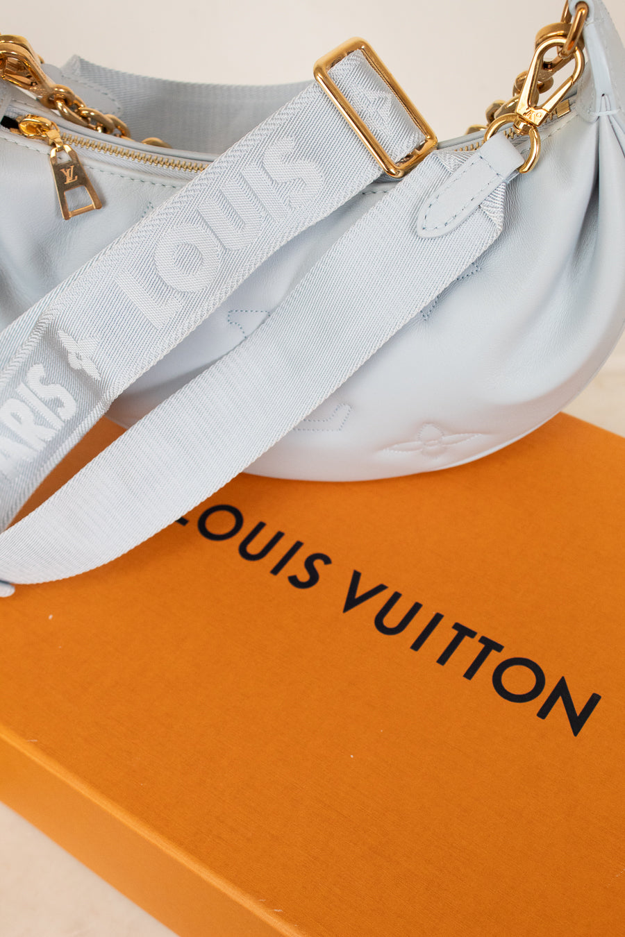Light blue handbag with gold hardware on a Louis Vuitton box