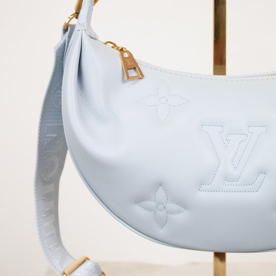 Light blue handbag with gold accents on a white background