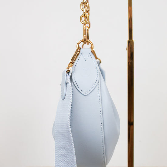 Light blue handbag with gold chain strap on a white background