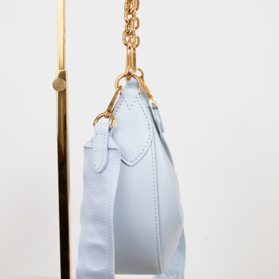 Light blue handbag with gold chain strap on a white background