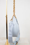 Light blue handbag with gold chain strap on a white background
