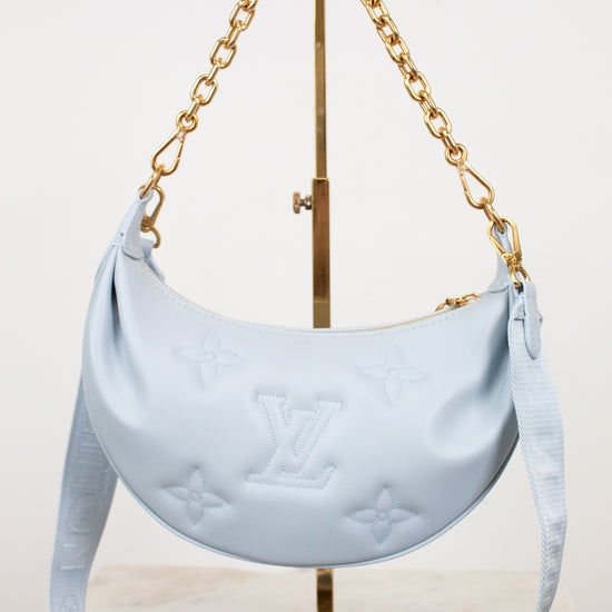 Light blue handbag with gold chain on a white background