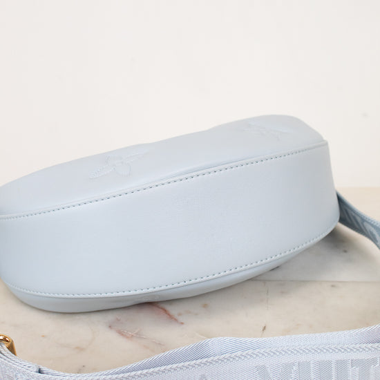 Light blue bottom exterior of handbag with strap on a light marble surface