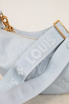 Close-up of a light blue handbag with gold chain and strap, featuring a brand logo.