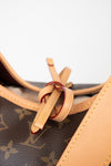 Close-up of a Louis Vuitton monogram canvas bag with tan leather trim and a decorative leather loop detail on a white background.