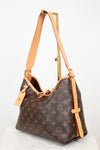 Louis Vuitton monogram canvas shoulder bag with tan leather trim and strap, displayed on a stand against a white background.