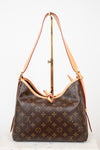 Louis Vuitton monogram canvas shoulder bag with tan leather trim and strap, displayed on a stand against a white background.