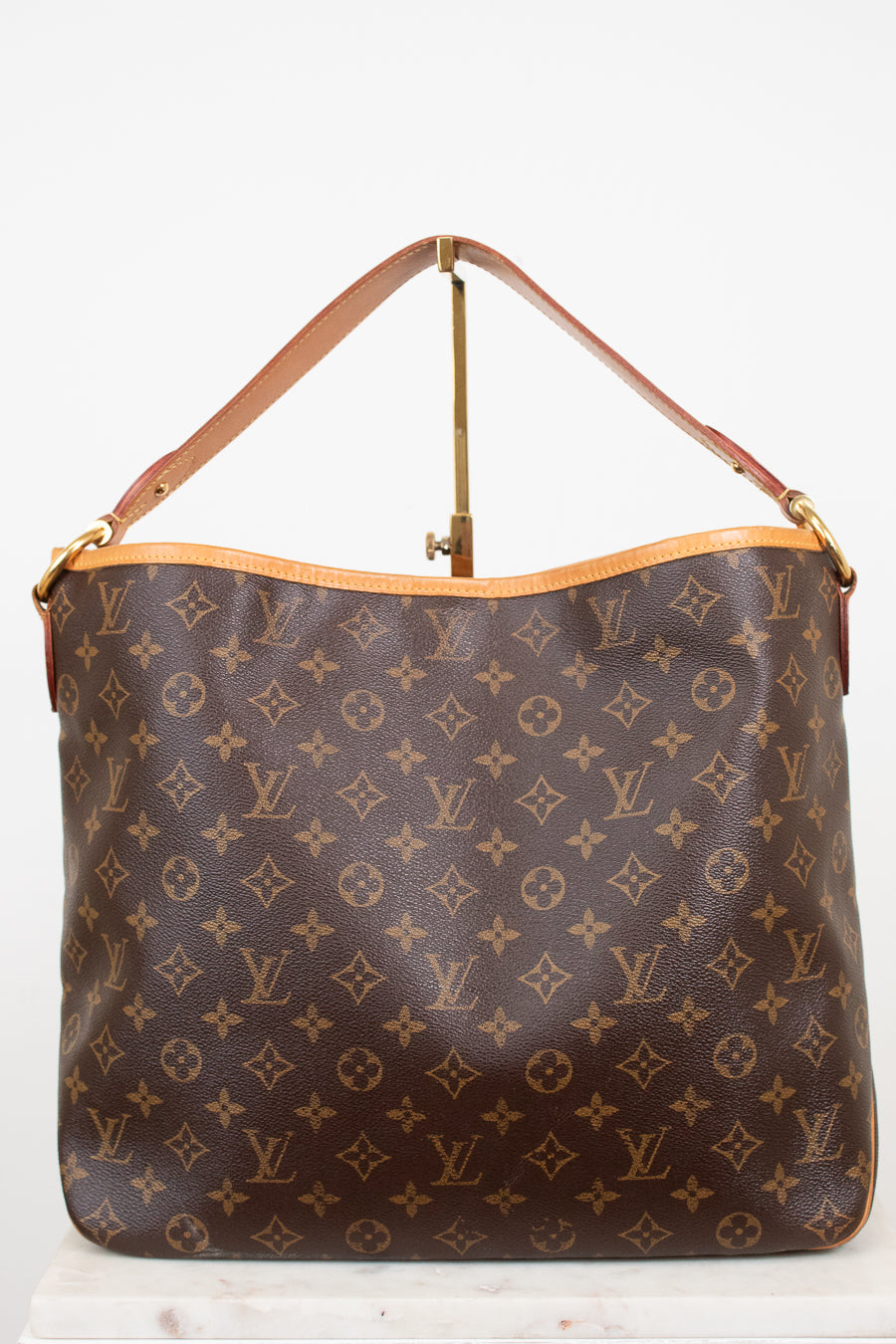 A Louis Vuitton monogram coated canvas shoulder bag with a tan leather strap and gold-tone hardware, displayed against a plain white background.