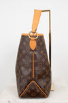 Louis Vuitton monogram coated canvas shoulder bag with tan leather trim and a gold-tone metal ring detail, displayed on a white marble surface with a gold stand against a white background.