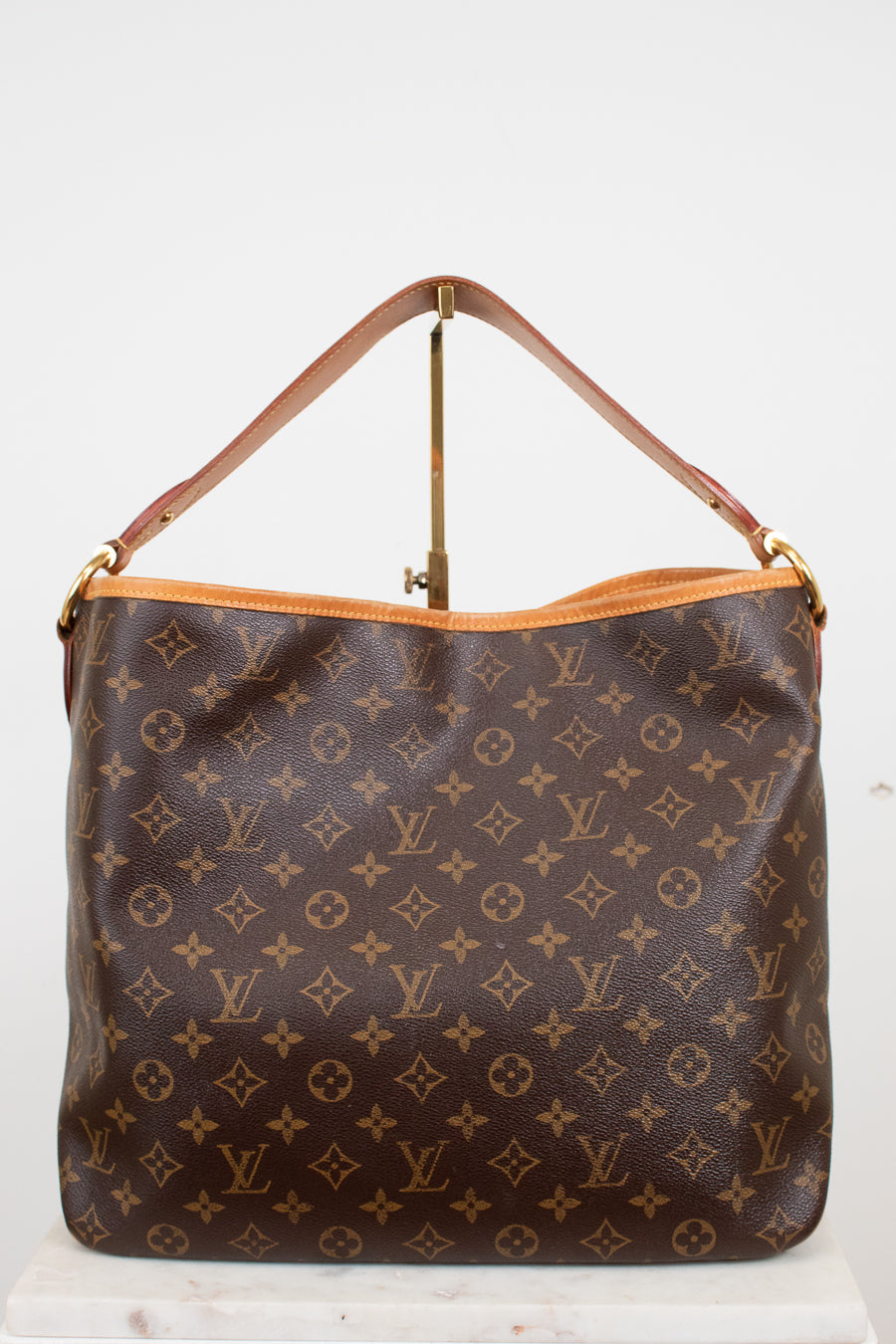 Louis Vuitton monogram coated canvas shoulder bag with a brown leather handle and gold-tone hardware, displayed against a plain white background.