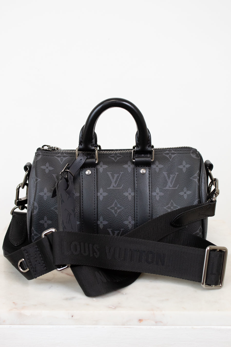 Black Louis Vuitton handbag with monogram pattern on a white background