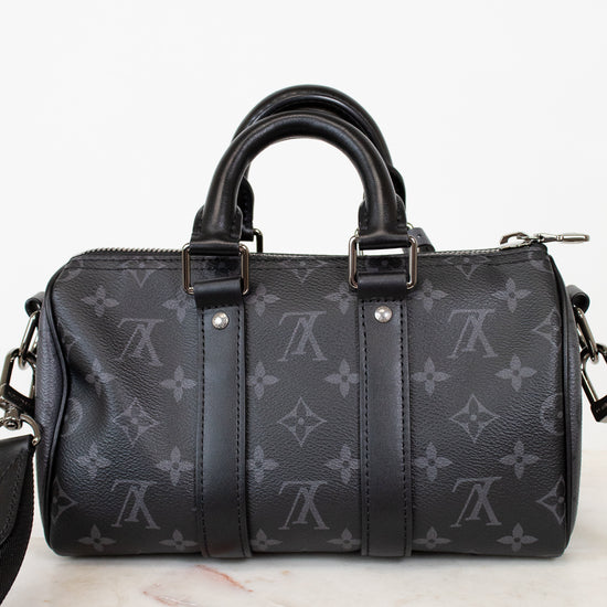 Black handbag with monogram pattern on a white marble surface
