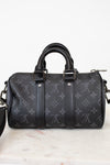 Black handbag with monogram pattern on a white marble surface
