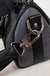 Close-up of a black handbag with a silver clasp on a light background