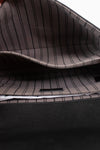 Close-up of the interior of a bag with a dark gray and black pinstripe pattern lining and a black textured exterior.