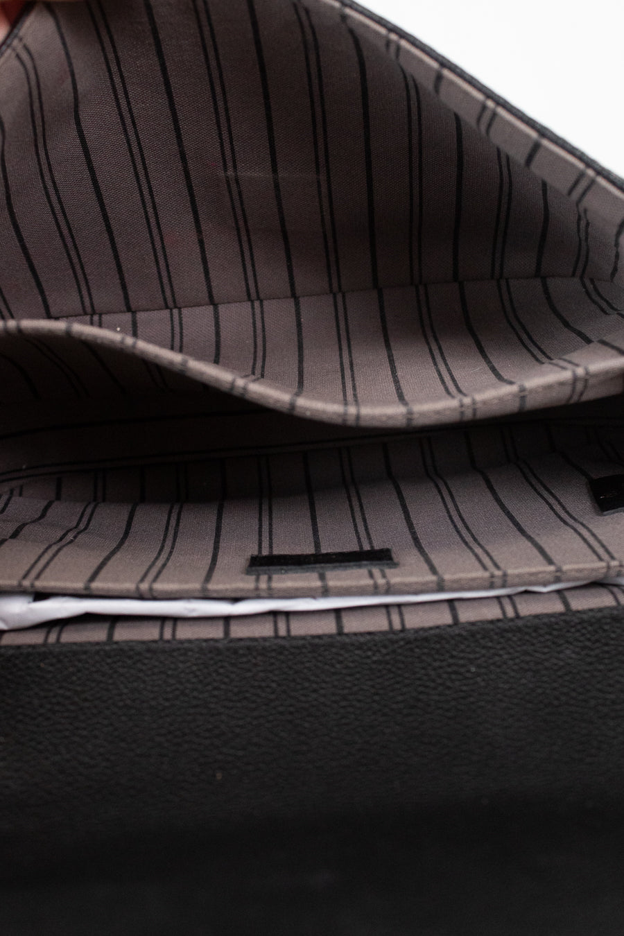 Close-up of the interior of a bag with a dark gray and black pinstripe pattern lining and a black textured exterior.